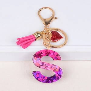 Detail of pink resin letter S keychain with glitter, leather tassel and heart charm