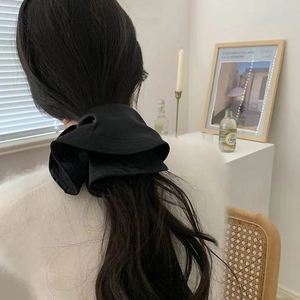 Detailed back view of a oversized black satin scrunchie styled in a high ponytail