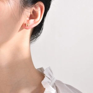 Close-up of golden H-shaped earring featuring sparkling pave-set cubic zirconia on model ear