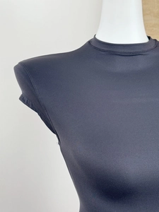 Close-up of black slim-fit top showing neckline and textured synthetic fabric on mannequin