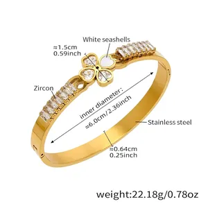 Macro detail of gold bangle with clover design featuring heart-shaped zircon and seashell