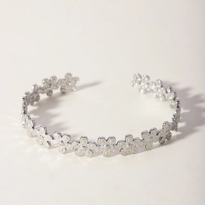 Detailed view of a silver open cuff bracelet with intricate floral leaf pattern design