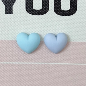Macro detail of matte heart-shaped resin charms in soft pastel blue and purple tones