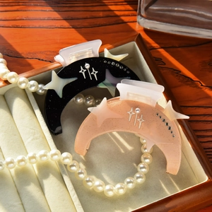 Detail of moon-shaped acetate hair claws with rhinestones and pearls in a jewelry box