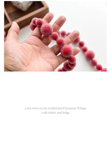 Detail of frosted red Christmas berry pick held in hand showing realistic texture
