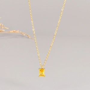 Detail of a square yellow gemstone pendant on a gold chain with four-prong setting