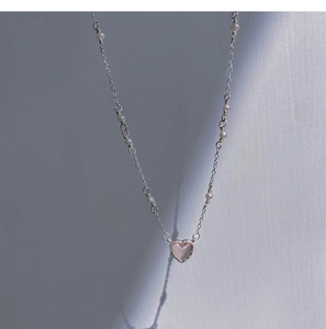 Close-up of pink heart pendant necklace with delicate silver chain and pearl accents