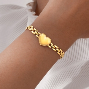 Detail of a gold heart-shaped watchband link bracelet worn on a woman's wrist