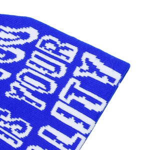 Detail of blue knit beanie showing white jacquard lettering and fine fabric texture