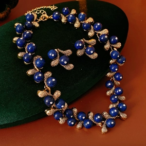 Detail of vintage flower jewelry set with blue gems and gold branches on green velvet