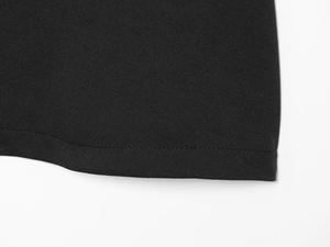 Close-up of black knitted fabric texture and fine stitching detail on a minimalist skirt