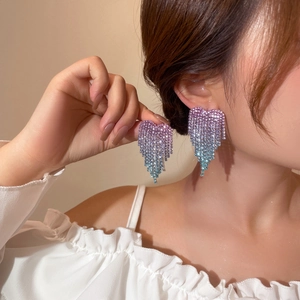 Detail of long heart tassel earrings featuring purple to aqua gradient rhinestones