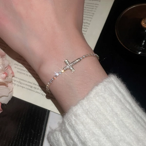 Macro detail of gold plated cross bracelet with sparkling cubic zirconia on wrist