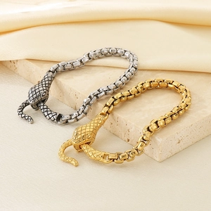 Close-up of gold and silver rattlesnake buckle bracelets on a stone and silk base