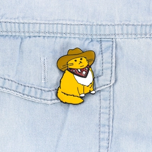 Close-up of yellow cowboy cat enamel pin with red bandana on blue denim jacket pocket