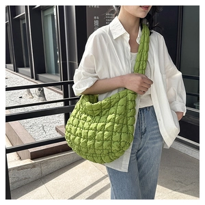 Outdoor shot of a woman wearing a bright green quilted puffer cloud bag with casual outfit