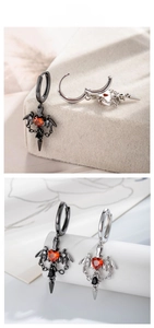Macro shot of gothic bat wing earrings with red heart stones and silver daggers