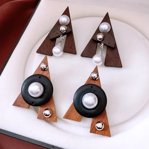 Close-up of geometric triangle wood and pearl earrings in a white jewelry box
