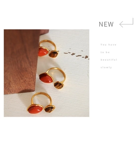 Detail of vintage gold plated steel ring with red stone and tiger eye on a wooden stand