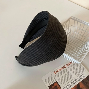 Nahaufnahme des dunkelgrauen breiten Strickstirnbands auf weißem Aufbewahrungskorb