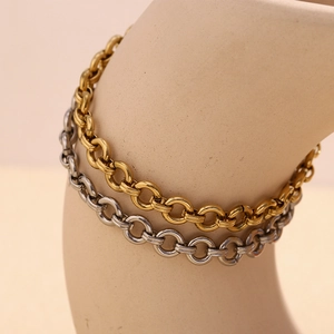 Detailed macro of thick gold and silver stainless steel chain anklets on a smooth bottle