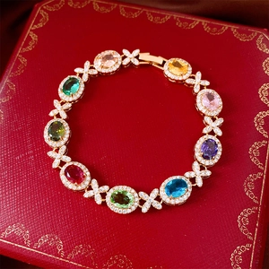 Dettaglio di un bracciale con zirconi colorati dorati e maglie micro-pavé intrecciate