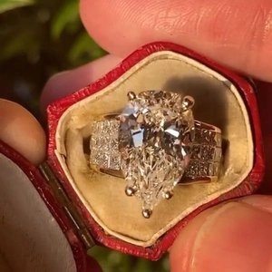 Close-up of a pear-cut zircon ring with side pavé diamonds in a vintage red gift box