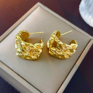 Detailed macro view of gold metallic irregular pleated C-shaped earrings in a jewelry box