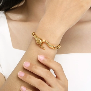 Schickes goldfarbenes Schlangenarmband mit Leopardenkopf-Verschluss am Handgelenk eines Models