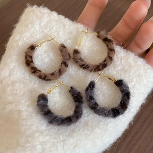 Detailed close-up of leopard print faux fur round hoop earrings with gold hooks