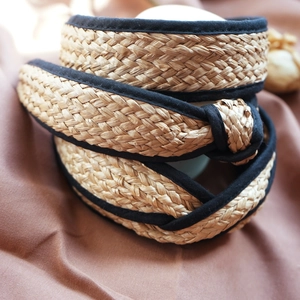 Close-up of beige raffia braided headband with black fabric trim and knot design detail