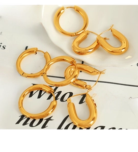 Detailed top view of gold minimalist hoop earrings and U-shaped buckles on a white dish