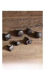 Detail view of 7 vintage cast iron cabinet knobs in various rustic styles on wood