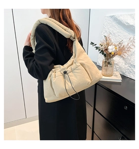 Detail of beige quilted nylon shoulder bag with knotted strap and drawstring pocket