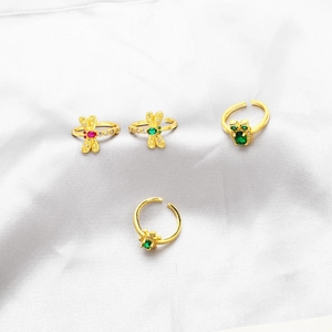 Close-up of four adjustable gold rings featuring emerald zircon dragonfly and animal motifs