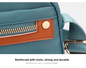 Close-up of green nylon crossbody bag featuring reinforced rivets and metal zipper
