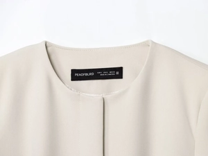 Détail de l'encolure d'un blazer beige avec étiquette de taille et couture de qualité