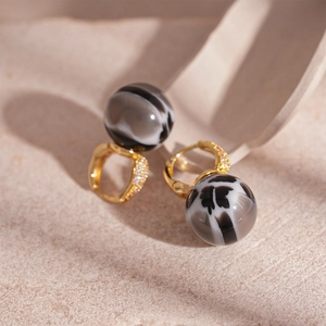 Macro shot of gold zircon hoop earrings with marbled black and white resin beads