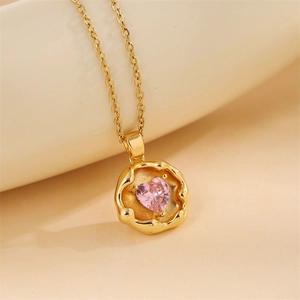 Macro detail of gold necklace featuring a heart-shaped pink zircon gemstone pendant