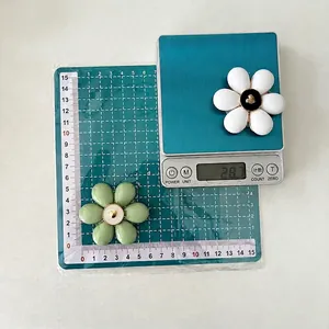 Floral phone socket grip in mint green and white colors on a portable digital scale