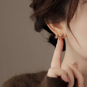 Close-up of gold-plated butterfly earring with colorful zircons on model ear