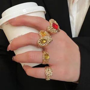 Textured gold hammered resin heart ring set with red and yellow gemstones worn by model
