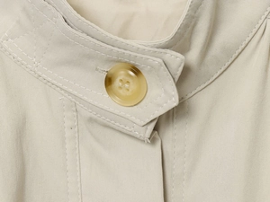 Detail der beigen Jacke mit plissiertem Stehkragen und Marmorknopf aus Twill-Gewebe