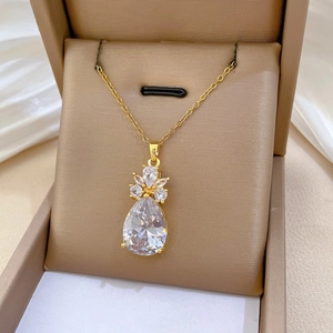 Gros plan d'un collier avec pendentif en cristal poire dans un écrin à bijoux marron