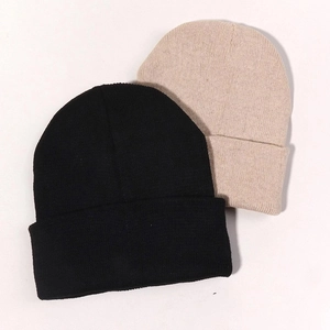 Close-up of ribbed knit beanies in black and beige showing fine fiber texture