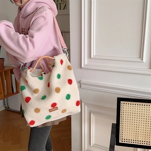 Close-up of fuzzy polka dot shoulder bag with adjustable pink strap and plush texture
