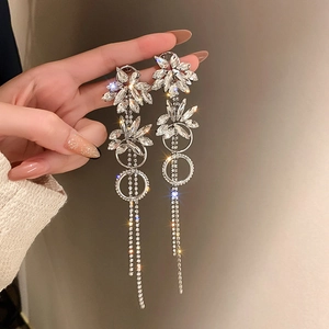Close-up of silver tassel earrings with crystal flower charms and sparkling rhinestones