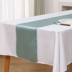 Close-up of light teal satin table runner with silky texture on a wooden dining table