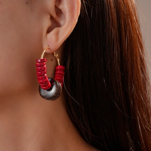 Ethnic style coconut shell beaded hoop earring on model with red and brown geometric design