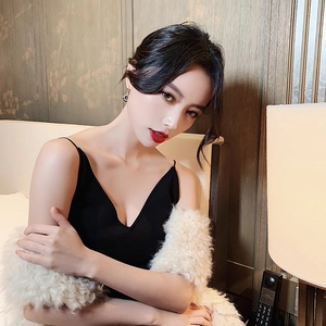 Close-up of black V-neck knitted camisole paired with a white faux fur shawl on model